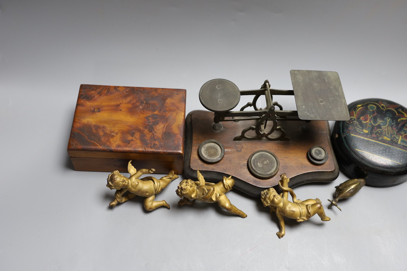 A set of three 19th century cast bronze cherubs, a set of lacquer coasters, a postal scale and a yew box